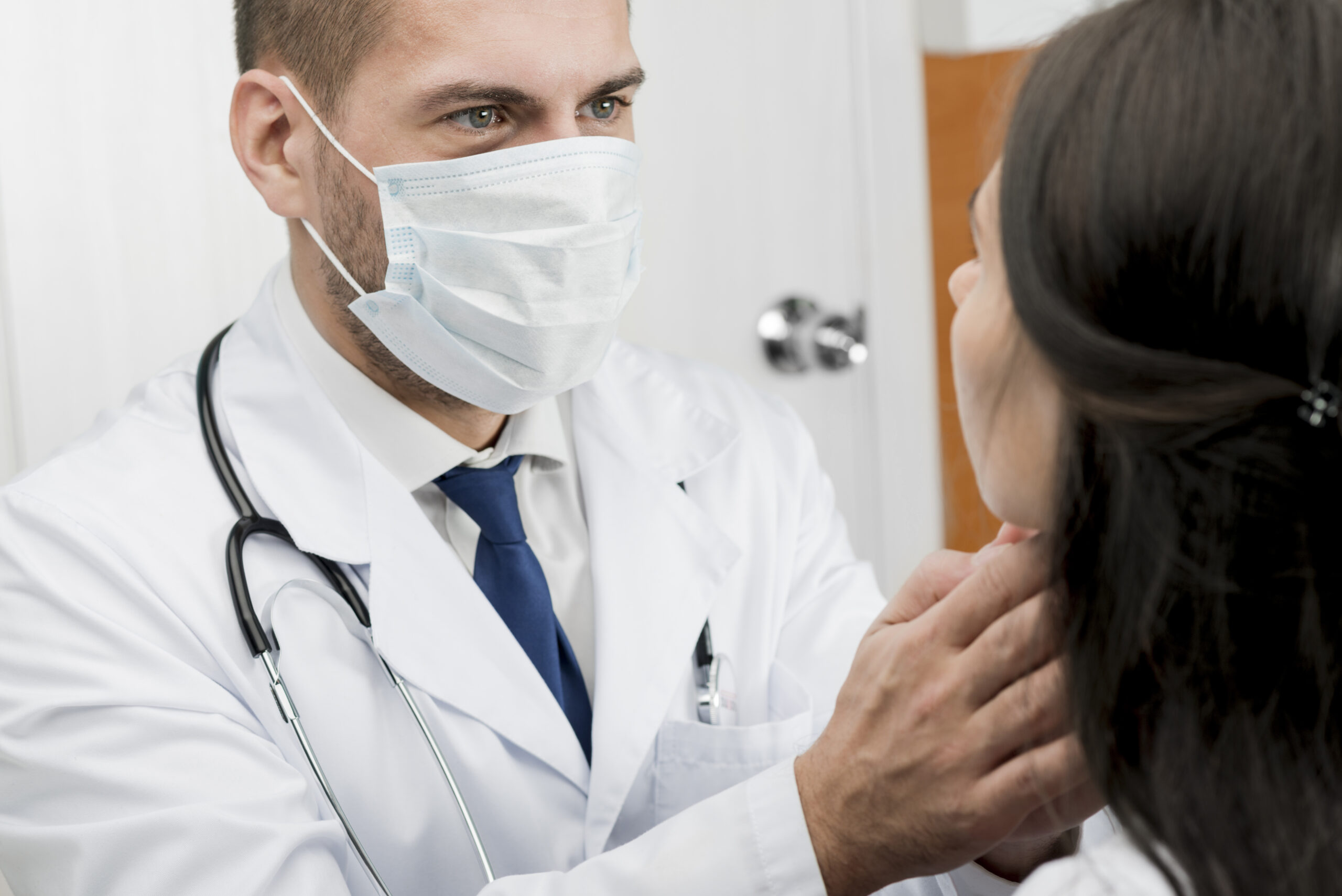 Терапевт в маске осматривает пациента